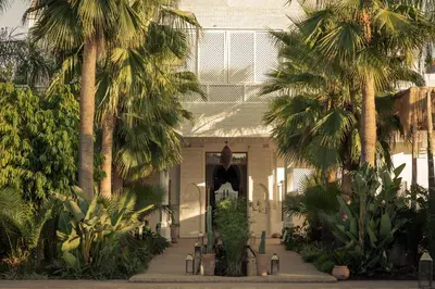 a white building with palm trees in front of it at Les Palmiers Boutique Hôtel & Spa in Marrakech