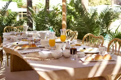 a wooden table with food and orange juice on it at Les Palmiers Boutique Hôtel & Spa in Marrakech