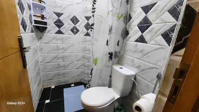 a bathroom with a white toilet and a tile wall at Appartement 7 min de l'aéroport de Marrakech in Marrakech