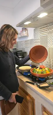 a woman standing in a kitchen preparing food on a stove at Riad Dar Fena By K&G &jacuzzi in Marrakech
