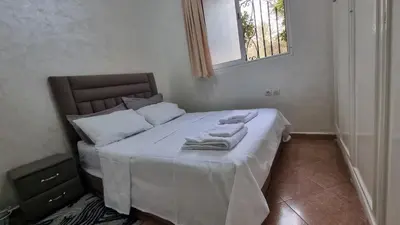 a bedroom with a bed with white sheets and a window at Airport apartment in Marrakech