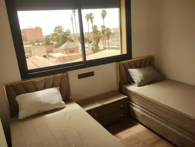two beds in a small room with a window at Nour 5 marrakech in Marrakech