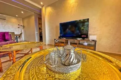 a living room with a glass table and a tv at Magnifique appartement spacieux avec une belle terrasse ensoleillée in Marrakech
