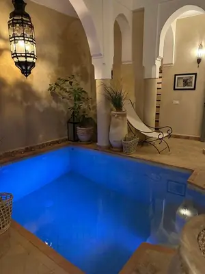 a swimming pool with blue water in a building at Riad des Fragrances dar el Bacha in Marrakech