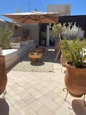 an outdoor patio with a couch and an umbrella at Riad des Fragrances dar el Bacha in Marrakech