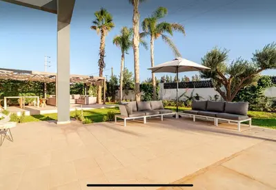 a patio with couches and an umbrella and palm trees at Manzal Vista in Marrakech