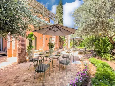 a patio with a table and chairs and an umbrella at Maison Maria Palmeraie in Marrakech