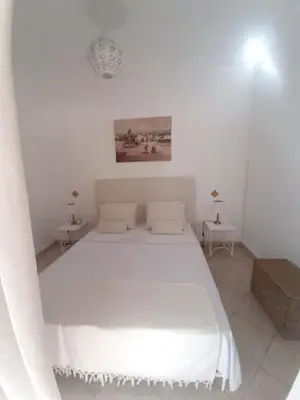 a white bedroom with a white bed and two tables at DUPLEX MEDINA AVEC TERRASSE in Marrakech
