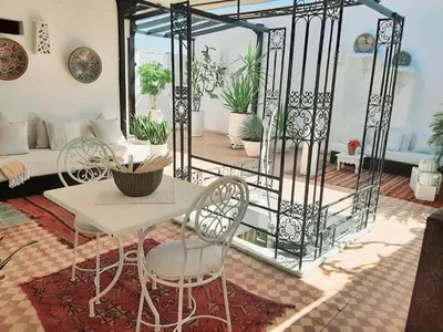 a living room with a table and chairs on a patio at DUPLEX MEDINA AVEC TERRASSE in Marrakech