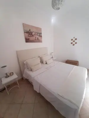 a white bedroom with a large white bed and a table at DUPLEX MEDINA AVEC TERRASSE in Marrakech