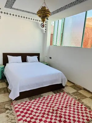 a bedroom with a bed and a red and white rug at Maison Cascada in Marrakech