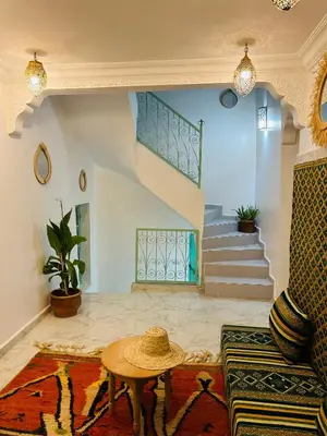 a living room with a table and a staircase at Maison Cascada in Marrakech