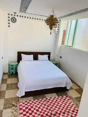 a bedroom with a white bed and a red rug at Maison Cascada in Marrakech