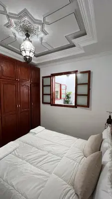 a bedroom with a large white bed with a ceiling at Riad dar Benaarab 2 aéroport 800 M in Marrakech