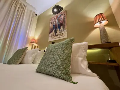 a bedroom with a bed with pillows and a lamp at Riad Taghia in Marrakech