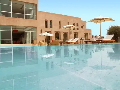 a swimming pool with chairs and umbrellas next to a building at Villa Loanaelle in Marrakech
