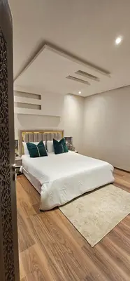 a bedroom with a large white bed with blue pillows at Appartement moderne, confort avec piscine et clim in Marrakech