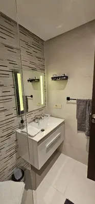 a white bathroom with a sink and a mirror at Appartement moderne, confort avec piscine et clim in Marrakech