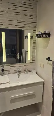 a white bathroom with a sink and a mirror at Appartement moderne, confort avec piscine et clim in Marrakech