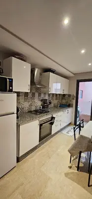 a kitchen with white appliances and a table and chairs at Appartement moderne, confort avec piscine et clim in Marrakech