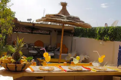 a table with some drinks and a straw umbrella at Riad Les Gazelles D'Orient Marrakech in Marrakech