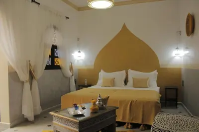 a bedroom with a large bed and a table at Riad Les Gazelles D'Orient Marrakech in Marrakech