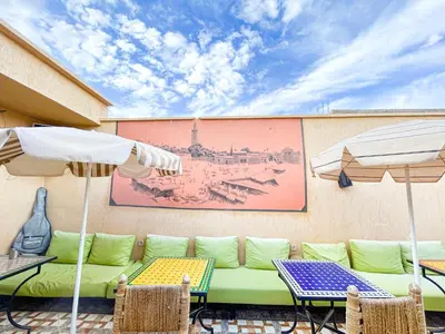 a patio with a couch and tables and umbrellas at Sun Hostel in Marrakech