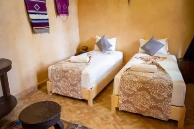 a bedroom with two beds and a table at Riad en Exlusivité à 5min de la place jamaa el fna in Marrakech