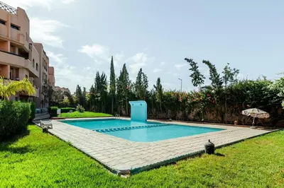 a swimming pool in a yard next to a building at OASIS PALM MARRAKECH APARTMENT- 5 Piscines in Marrakech