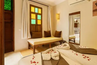 a room with two beds and a chair and a mirror at Riad Belikoss Pool & SPA in Marrakech