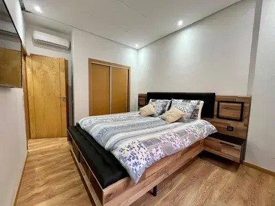 a bedroom with a large bed with a wooden floor at Bel Appartement à Marrakech en Résidence avec Piscine - Fibre & Netflix in Marrakech
