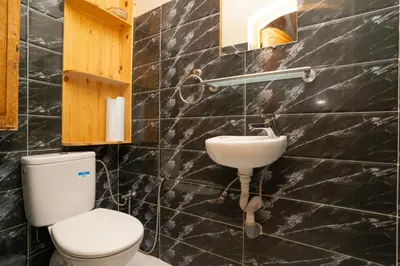 a black tiled bathroom with a toilet and a sink at Villa Korima in Marrakech