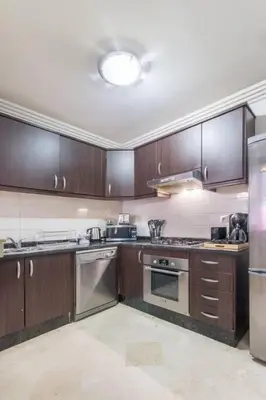 a kitchen with wooden cabinets and stainless steel appliances at Luxury Duplex - Private Jacuzzi - Center Hivernage in Marrakech