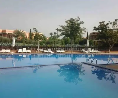 a large blue swimming pool with white chairs and trees at NEW appartement in palmeraie in Marrakech