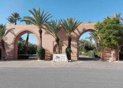 a building with palm trees and a sign in front at NEW appartement in palmeraie in Marrakech