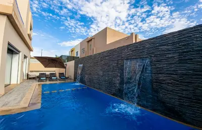 a swimming pool in front of a brick wall at Villa HAW Marrakech in Marrakech