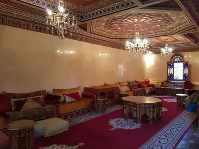 a living room with a couch and a table and chandeliers at Villa Amerchiche in Marrakech