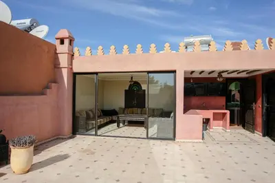 a house with a patio with glass doors and a balcony at Villa Amerchiche in Marrakech