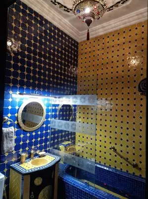 a blue tiled bathroom with a sink and a mirror at Riad Tesnime in Marrakech