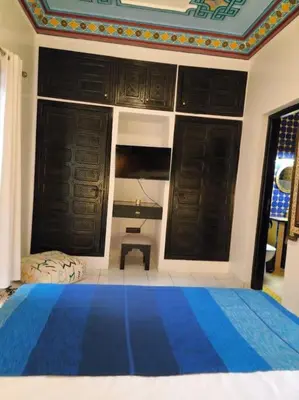 a bedroom with a blue bed and a desk in it at Riad Tesnime in Marrakech