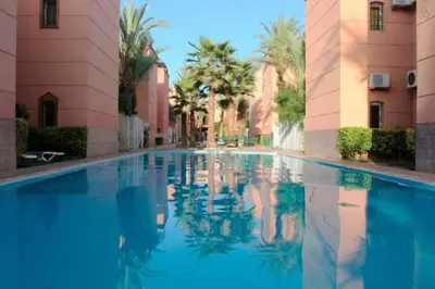 a swimming pool in the middle of a building with palm trees at Riad Tesnime in Marrakech