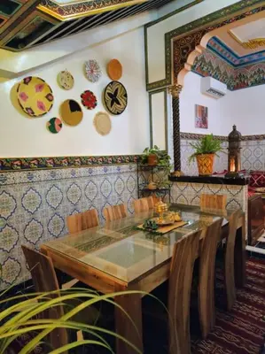 a dining room with a table and chairs and plates on the wall at Riad Tesnime in Marrakech