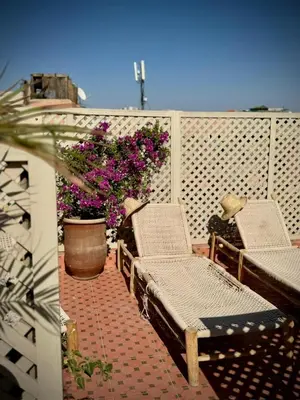 a balcony with two chairs and a pot of flowers at Riad Dollar Des Sables & Spa in Marrakech
