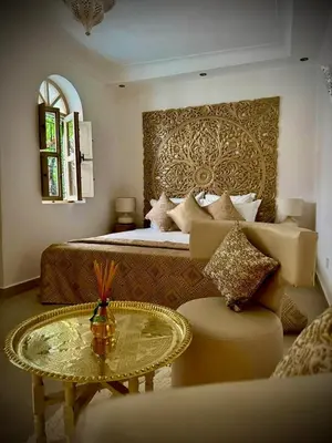 a bedroom with a bed and a table and a couch at Riad Dollar Des Sables & Spa in Marrakech