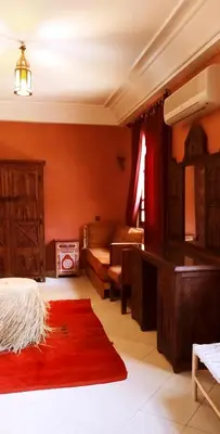 a living room with red walls and a red rug at maison d'hôtes Le petit jardin Marrakech in Marrakech