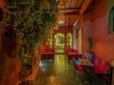 a restaurant with red chairs and tables and plants at Riad Dar Sido in Marrakech