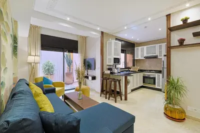 a living room with a blue couch and a kitchen at Oasis - Appartement Authentique à Gueliz in Marrakech