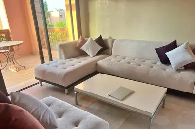 a living room with a couch and a table with a laptop at Bright condo w/ pool in Marrakech
