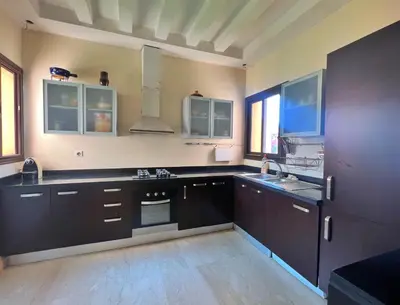 a large kitchen with black cabinets and a sink at Bright condo w/ pool in Marrakech