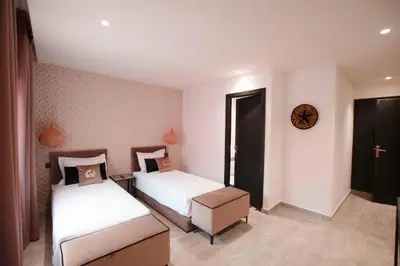a bedroom with two beds and a door to a room at Riad La Petite Majorelle in Marrakech